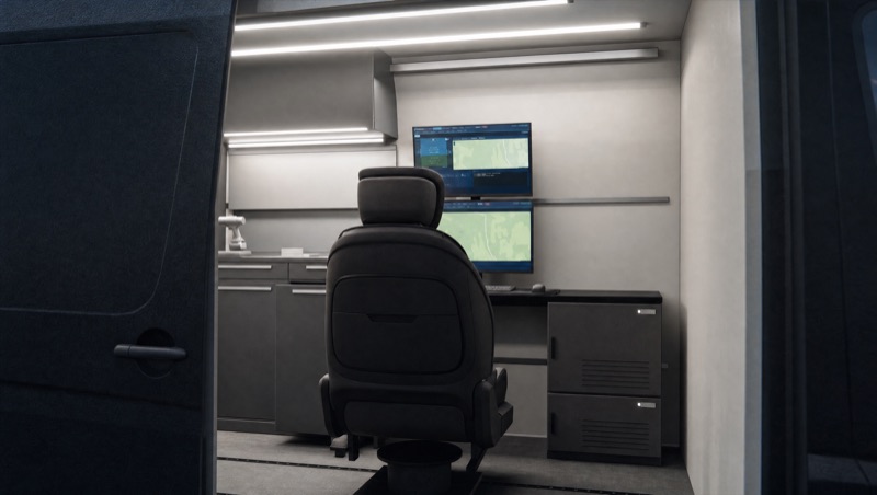 View through the open sliding door: operator seat on floor rails facing the ground control station.